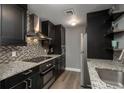 Modern kitchen featuring stainless steel appliances, dark cabinetry, granite countertops, and mosaic tile backsplash at 800 N Pearl St # 1211, Denver, CO 80203