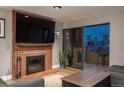 Comfortable living room features a brick fireplace, a large television, and access to the balcony with a beautiful city view at 800 N Pearl St # 1211, Denver, CO 80203