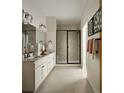 Well-lit bathroom with double vanity, decorative mirrors, and a glass-enclosed shower at 6153 N Ceylon St # 204, Denver, CO 80249