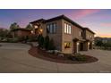 Exterior view of a luxurious home with stone accents and a paved driveway leading to the garages at 6371 Diamond Ridge Pkwy, Castle Rock, CO 80108