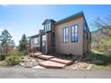 Beautifully landscaped home with a charming exterior and well-maintained grounds and wooden deck and walkways at 6584 Pike Cir, Larkspur, CO 80118