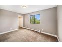 Neutral bedroom featuring soft carpet, closet, window with green tree views, and baseboard heating at 381 S Ames St # F204, Lakewood, CO 80226