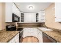 Compact kitchen with white cabinets, granite countertops, modern appliances, and hardwood floors at 381 S Ames St # F204, Lakewood, CO 80226