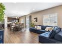 Open floor plan with dark hardwood floors, oversized sofa, dining table, and kitchen at 12835 Randles Ave, Parker, CO 80134