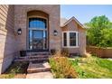 Inviting front entrance with brickwork, a large arched window, and landscaped garden beds, enhancing curb appeal at 9688 Chesapeake St, Highlands Ranch, CO 80126