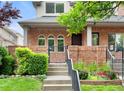 Close-up of the brick home's front entrance with steps, iron gate, and lush landscaping at 538 Cook St, Denver, CO 80206