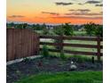 Scenic backyard view at sunset with a wooden fence and landscaping, and a peek of other neighborhood houses at 21 N Edge Cliff St, Castle Rock, CO 80104