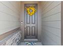A welcoming front door is adorned with a yellow floral wreath and accented by stone details at 21 N Edge Cliff St, Castle Rock, CO 80104
