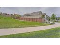 Side view of home showing the roof, the wooden fence, a retaining wall, and a neatly mowed backyard at 8153 S Ider Ct, Aurora, CO 80016