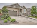 Attractive home showcasing a driveway, two-car garage, stone accents, and meticulous landscaping with green bushes at 8153 S Ider Ct, Aurora, CO 80016