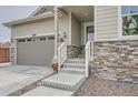 Close-up of front of house showing stone accents, gray siding, an inviting front porch and stairs to the front door at 8153 S Ider Ct, Aurora, CO 80016