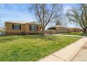 Quaint street view showcases the brick house with a spacious front yard in a residential neighborhood at 2562 S Xavier St, Denver, CO 80219