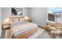 Virtually staged bedroom with light wood bed frame and side tables at 5242 Longs Peak St, Brighton, CO 80601