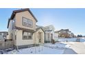 Two-story home with light beige siding and snow-covered walkway at 7312 Watercress Dr, Littleton, CO 80125