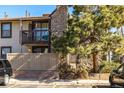 Exterior of the condo shows a private balcony, stone accents, and partial fencing, surrounded by mature landscaping at 7790 W 87Th Drive Dr # D, Arvada, CO 80005