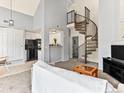 Bright living room featuring a spiral staircase, vaulted ceiling, and kitchen access at 8361 S Upham Way # 209, Littleton, CO 80128