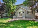 Backyard showcasing a stone patio area surrounded by lush lawn and mature trees providing shade at 6525 S Abilene St, Englewood, CO 80111