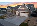 Charming home with a two-car garage, gray siding, tasteful stone accents, and tidy landscaping at 11412 Autumn Moon St, Littleton, CO 80125