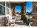 Inviting front porch with stone columns and an archway offering a relaxing outdoor space with seating and planters at 11582 Jimenez St, Parker, CO 80134