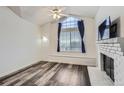 Bright room with a large window, ceiling fan, and adjacent brick fireplace at 4760 S Wadsworth Blvd # M302, Littleton, CO 80123