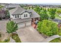 Aerial view of home with a large driveway, two-car garage, mature trees, and well-maintained landscaping at 7949 S Blackstone Pkwy, Aurora, CO 80016