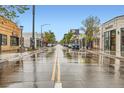 Scenic street view featuring storefronts and lush trees on a wet day, with yellow lines on the road at 4144 Tennyson St # 10, Denver, CO 80212