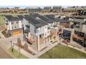 Community aerial showcasing modern townhomes with solar panels, patios, green spaces, and nearby commercial buildings at 10051 Belvedere Cir, Lone Tree, CO 80124