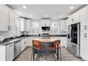 Bright kitchen with stainless steel appliances, white cabinets, subway tile backsplash and an island with seating at 10051 Belvedere Cir, Lone Tree, CO 80124
