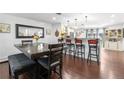 Open-concept dining area featuring hardwood floors, bar seating, and stylish decor with a large rustic table at 7132 Xavier Way, Westminster, CO 80030