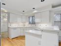 Bright kitchen featuring white cabinets, tile backsplash, and hardwood floors at 3026 S Alton Ct, Denver, CO 80231