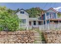 Charming two-story house featuring a cozy porch and a bright red door, framed by a rustic stone retaining wall at 1324 Virginia St, Idaho Springs, CO 80452