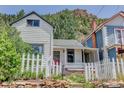 Quaint two-story home with a picket fence and mountain views, surrounded by lush greenery and stone walls at 1324 Virginia St, Idaho Springs, CO 80452
