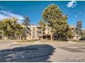 Apartment building exterior with multiple balconies and mature trees on a sunny day at 1302 S Parker Rd # 127, Denver, CO 80231