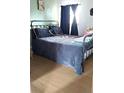 Bedroom featuring a black metal frame bed with hardwood flooring, dark curtains, and pale green walls at 1242 S Seneca Way, Denver, CO 80223