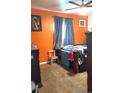 Bedroom featuring an orange accent wall, brown carpet, and dark blue curtains over the window at 1242 S Seneca Way, Denver, CO 80223