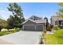 Two-story home boasts a three-car garage, manicured lawn, and landscaping featuring trees, plants, and flowers at 6772 Tiger Tooth, Littleton, CO 80124