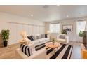 Bright living room with stylish decor, light wood floors, and modern striped rug at 12225 W 57Th Pl, Arvada, CO 80002