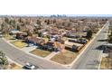 Expansive aerial view of a residential neighborhood, featuring tree-lined streets and well-kept lawns with Denver skyline in the distance at 96 S Depew Dr, Lakewood, CO 80226