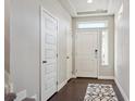 Bright entryway featuring a white door, overhead window, hardwood floors, and stylish black and white rug at 18066 E 104Th Way, Commerce City, CO 80022