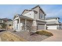 A two-story home featuring stone accents, a covered porch, a two-car garage, and a well-maintained landscape at 18066 E 104Th Way, Commerce City, CO 80022