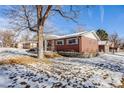 Side view of a brick ranch house with snowy yard at 2994 S Winona Ct, Denver, CO 80236