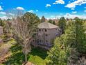 Expansive backyard features lush greenery, a stone retaining wall, and mature trees for privacy at 907 Greenridge Ln, Castle Pines, CO 80108