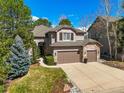 Beautiful two-story home with a three-car garage and manicured front lawn, surrounded by mature trees at 907 Greenridge Ln, Castle Pines, CO 80108