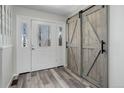 Inviting foyer with stylish wood-look flooring, decorative glass door and modern sliding barn doors at 7420 Windwood Way, Parker, CO 80134