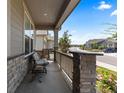 Comfortable covered porch with stone pillars, seating, and neighborhood views at 15802 Xanthia Way, Thornton, CO 80602
