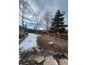 Large backyard featuring a retaining wall, trees and a wooden fence at 21041 E Ida Ave, Centennial, CO 80015