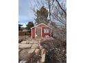 Exterior view of a small shed with a wooden door, stone path, and surrounding foliage at 21041 E Ida Ave, Centennial, CO 80015