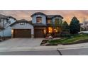 Charming two-story home with a three-car garage, stone accents, manicured lawn, and inviting landscaping at 9797 Sunset Hill Cir, Lone Tree, CO 80124