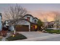 Two-story home with mature trees, a three-car garage, stone accents, and a well-maintained lawn at 9797 Sunset Hill Cir, Lone Tree, CO 80124