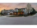 Beautiful two-story home with a well-maintained lawn, mature trees, and a three-car garage at dusk at 9797 Sunset Hill Cir, Lone Tree, CO 80124